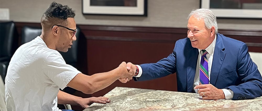 Sam Adamo, Sr. happily shaking hands with client at conference table