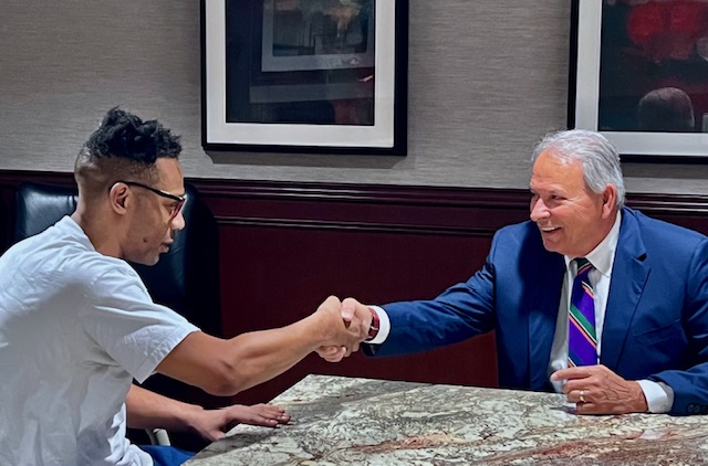 Sam Adamo, Sr. happily shaking hands with client at conference table